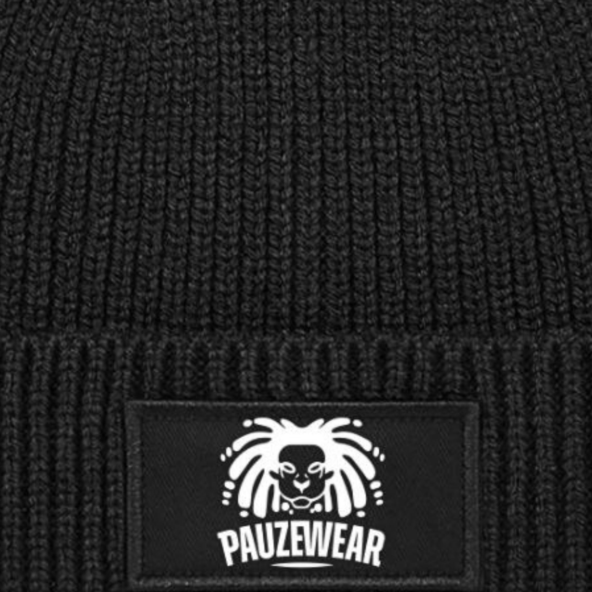 Black knit beanie with a white logo patch on a textured black background
